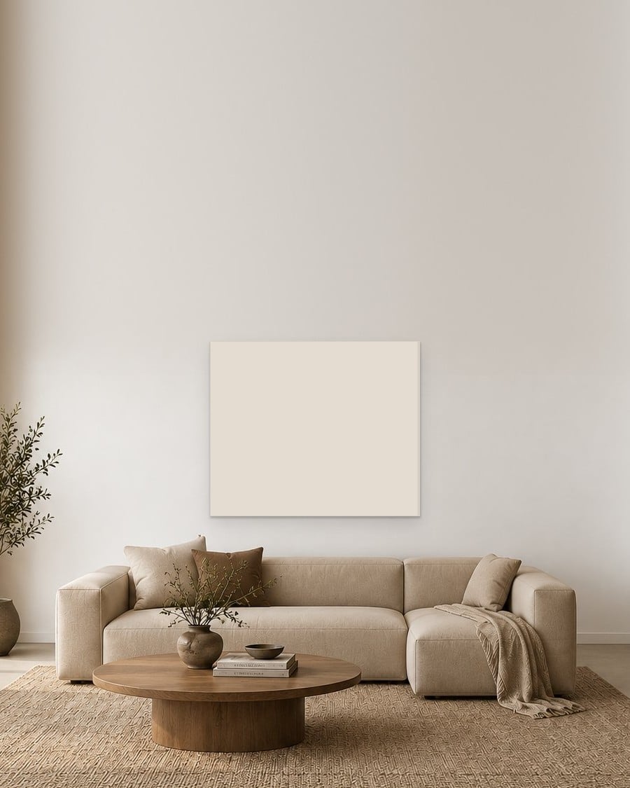 Een leeg doek aan de muur boven een lichte bank in een rustige woonkamer